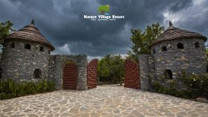 Stone entrance towers with wooden gates under dramatic cloudy skies
